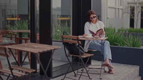Woman Reading a Book at an Outdoor Cafe Table