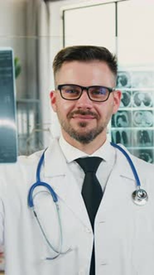 Smiling Doctor Holding X-Ray in Hospital Office