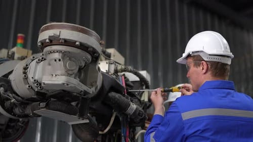 Ingenieur arbeitet an einer automatischen Roboterarmmaschine in der Fabrik. Männlicher Techniker, Arbeiter, Wartungsroboter