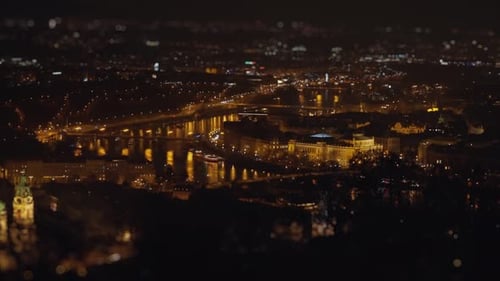 Prague downtown at night. Dim street lights illuminate the scene and are reflected on the river's su
