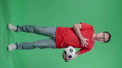 Young Man Holding Soccer Ball over Green Screen