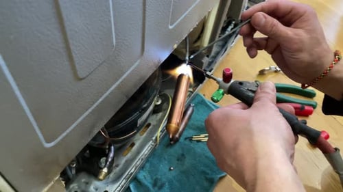 Technician Repairing Refrigerator with Welding Torch