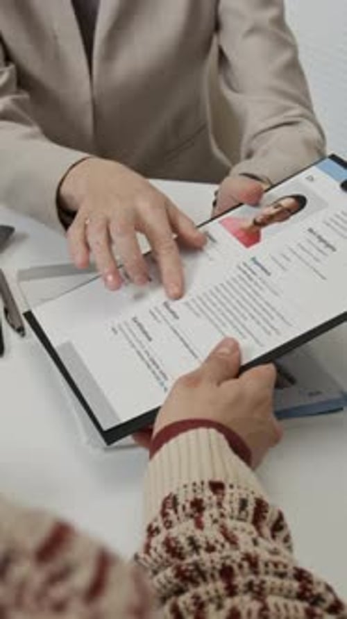 Vertical of Anonymous Female Hiring Manager Handing Resume to Unknown Applicant