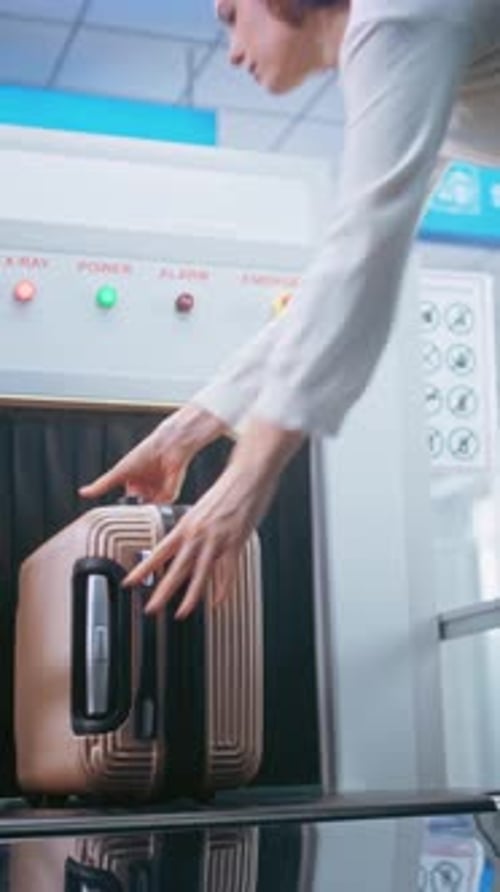 Airport Security Checkpoint Passenger Places Suitcase on Xray Conveyor Belt for Baggage Screening
