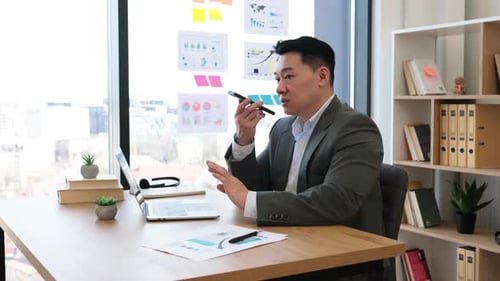 Asian Businessman Sending Voice Messages in Modern Office Setting