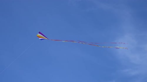 Flying Toy Children Kite Against Background Blue Sky with Soft Clouds at Sunny Day in Summer