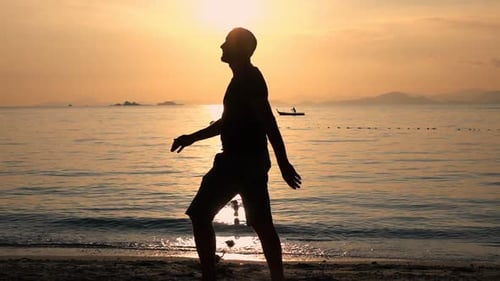 Man silhouette walking on exotic beach at sunset in super slow motion