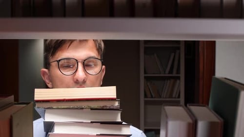 Student Searching Book in Library Holding Pile of Books