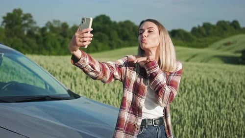 Blonde junge Dame in kariertem Hemd und Jeans macht Selfie