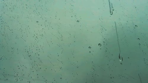 Macro raindrop patterns dripping down on large window on a dark overcast gray clouded sky.
Moody atm