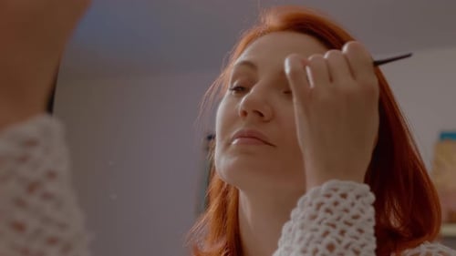 Woman Applies Makeup in the Mirror at Home