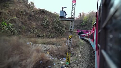 imagem de rastreamento de um trem expresso em movimento navegando por colinas e entrando em um túnel ferroviário de concreto
