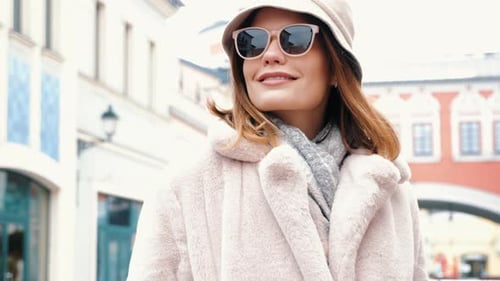 Stylish Woman Walking Through City Streets in Pink Coat