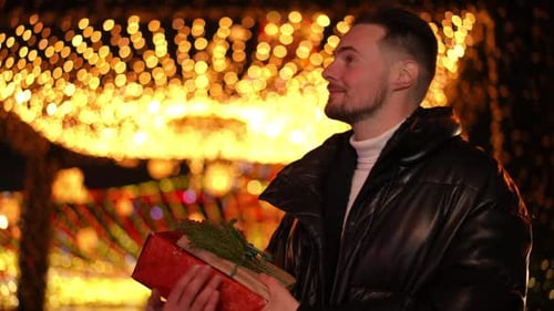 Portrait of Satisfied Happy Man Smiling Standing with Christmas Gifts on Urban City Street at Night