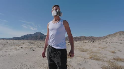 Man with Gas Mask Standing in Desert Environment Under Clear Sky