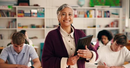 Smiling Teacher with Gray Hair Holding Tablet in Classroom