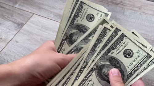 Woman Counting One Hundred Dollar Banknotes On The Table