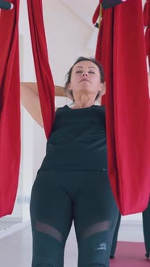 Woman Practicing Aerial Yoga Stretching Back Indoors