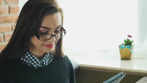 Young Happy Woman Using Tablet Computer in a Cafe