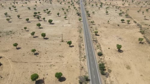 Aerial drone shot of a vehicle silhouetted against the golden desert horizon of Rajasthan.