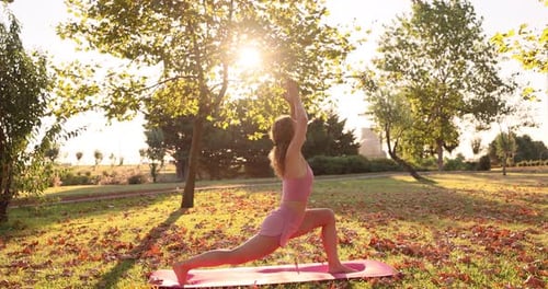 Woman Practicing Yoga Outdoors in Park at Sunset