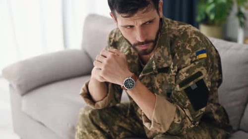 Close up view. A soldier in Ukrainian uniform is sitting on the sofa