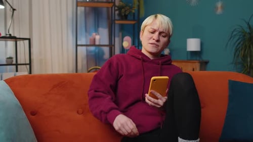 Frustrated Young Adult Using Smartphone on Couch