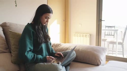 Young Woman Working on Laptop on Sofa
