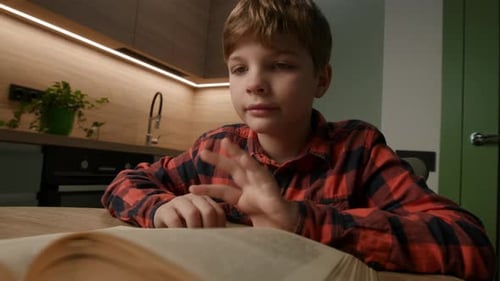 Boy Reading a Book at the Kitchen Table