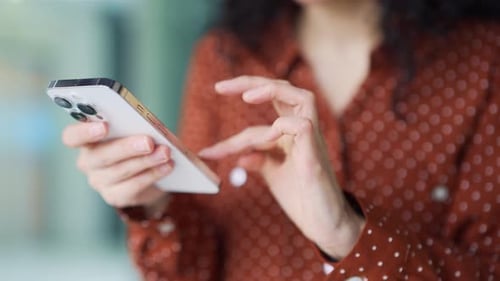 Close up of woman's hands holding smartphone, female running fingers on touch screen, using phone,