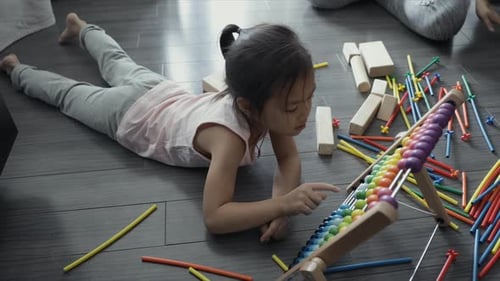 Mädchen spielt mit mehrfarbigem Abakus-Spielzeug auf dem Boden Abakus