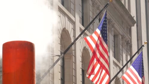 American Flag Waving Next to Steam Pipe in City