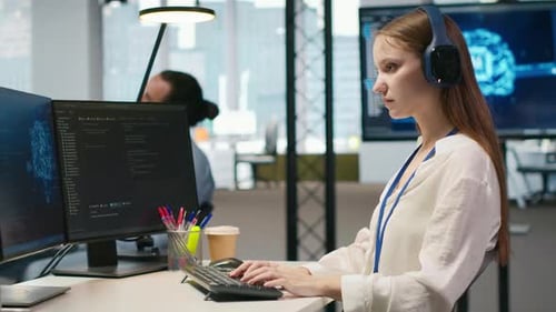Young Female Programmer in Office Reviewing AI System Metrics Listening Music