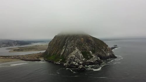 Morro Rock Counterclockwise Drone Shot as Boat Leaves Morro Bay on a Foggy California Day