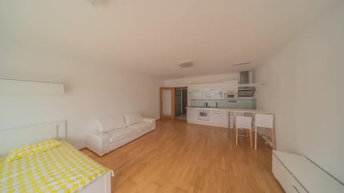 Un elegante apartamento tipo estudio con un ambiente espacioso, con elegantes muebles blancos y una cocina contemporánea