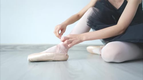 Ballet Dancer Tying Ribbons on Pointe Shoes