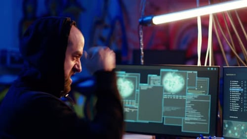 Man Working at Multiple Computer Screens at Night