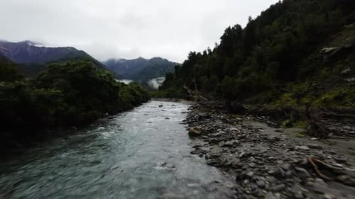 Cinematic FPV shot overhead a small river and forest in the New Zealand mountain range