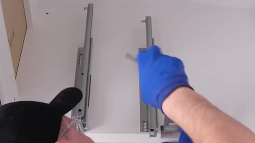A Qualified Master in Gray Overalls Installs Furniture in a Modern Bright Kitchen Vertical Video
