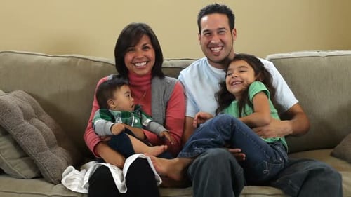 Happy Family Smiling on Sofa with Baby and Girl