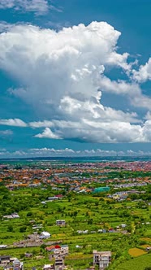 Champs et toits de Kuta Selatan sous un cumulus en hyperlapse aérienne, Bali, Indonésie