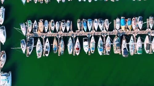 Flight along the long pier with multiple yachts at both sides.