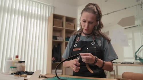 Craftswoman Creating Leather Belt with Special Tool in Workshop