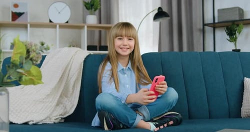 Child with Phone Smiling on Couch