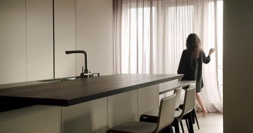 Woman Standing by Window in Modern Kitchen
