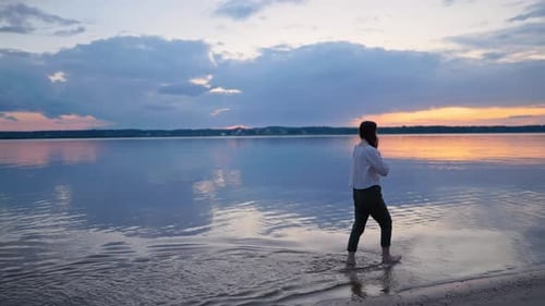 Woman Walks Barefoot on Beach at Sunrise