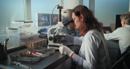 Female Microbiologist Analyzes Fossils Under Microscope in Equipped Archaeological Laboratory