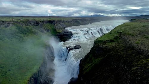 Majestic Waterfall Cascading Through Green Icelandic Landscape