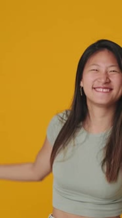 Smiling young woman dancing isolated over yellow background in studio