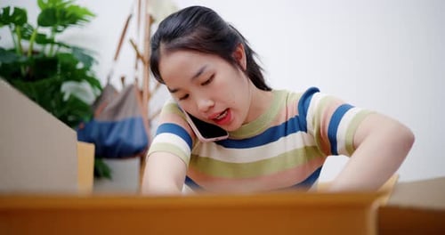 Young Woman Packing Boxes While Talking on Phone